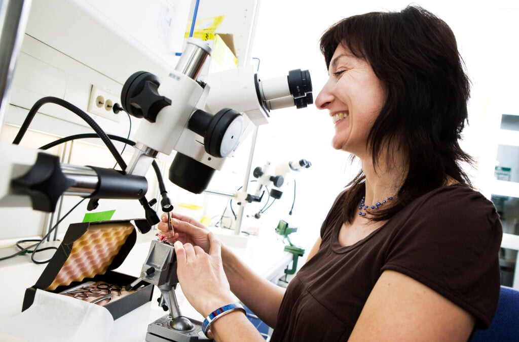 A woman looking into a microscope