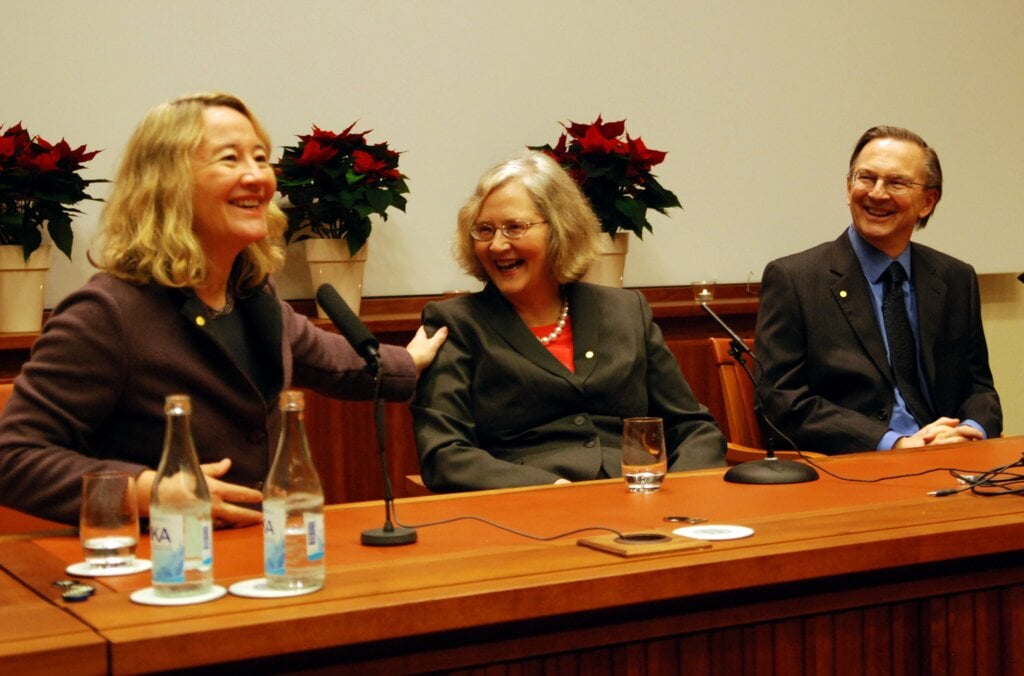 Two women and a man at sitting at a table smiling