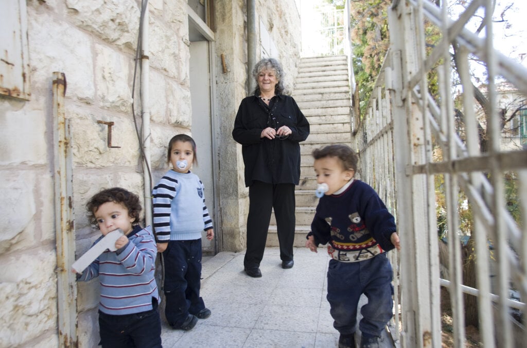 A woman and three small children in front of a house
