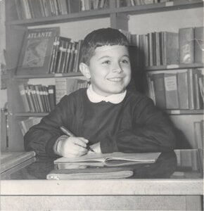 A black and white photograph of Giorgio Parisi as a child writing