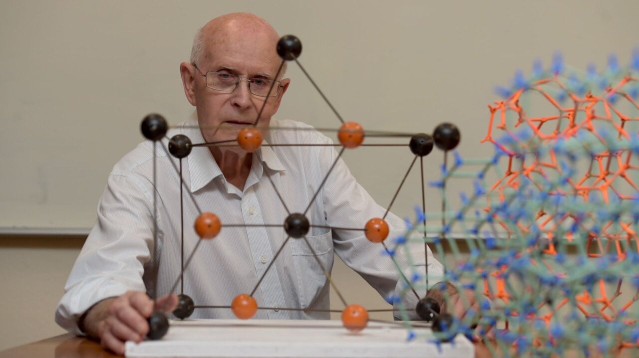 Photo of a man in front of a chemistry model
