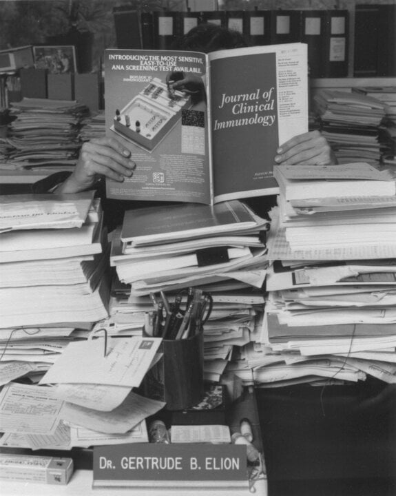 A woman behind a oile of books and journals