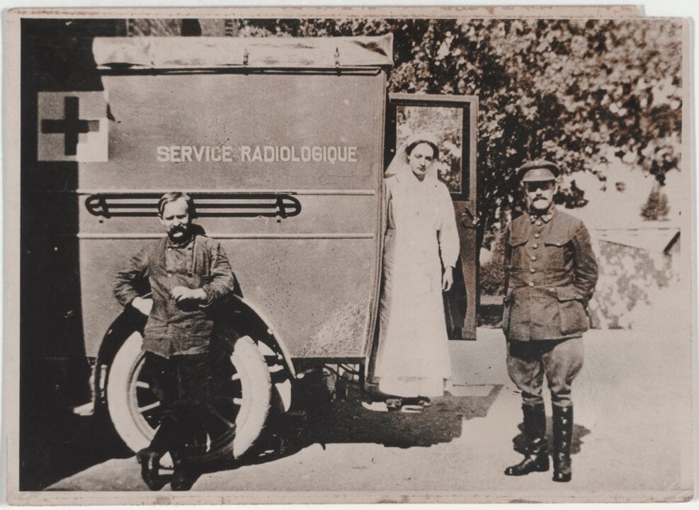 Two men and a woman in front of an ambulance
