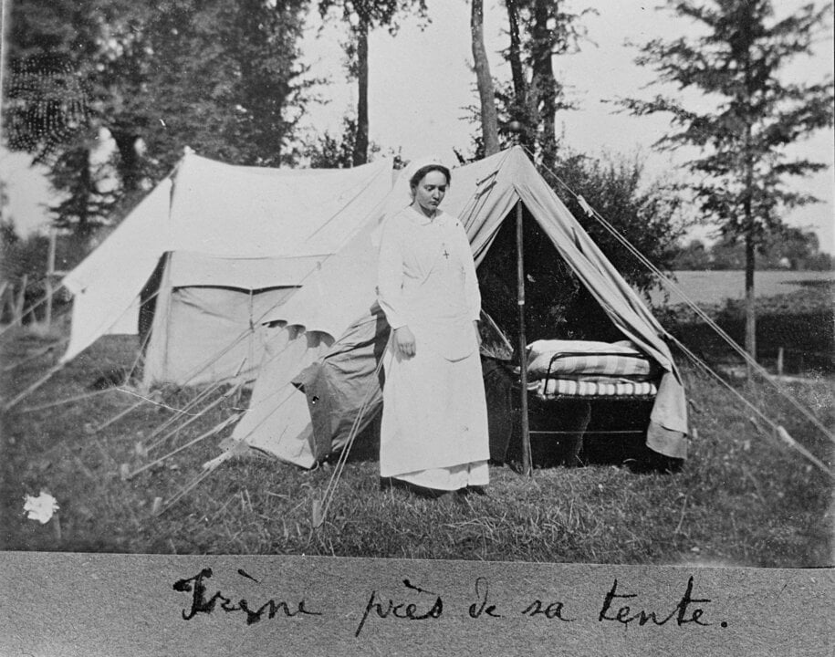 A woman in front of a tent in a wood