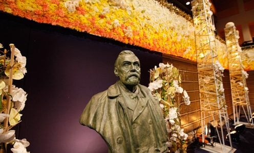 A bust of Alfred Nobel, surrounded by beautiful flowers
