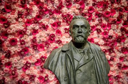 A bust of Alfred Nobel, surrounded by a beautiful wall of flowers