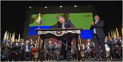 President Santos signs the Final Peace Agreement while the FARC's top leader, Rodrigo Londoño, aka. Timochenko, is standing by his side.